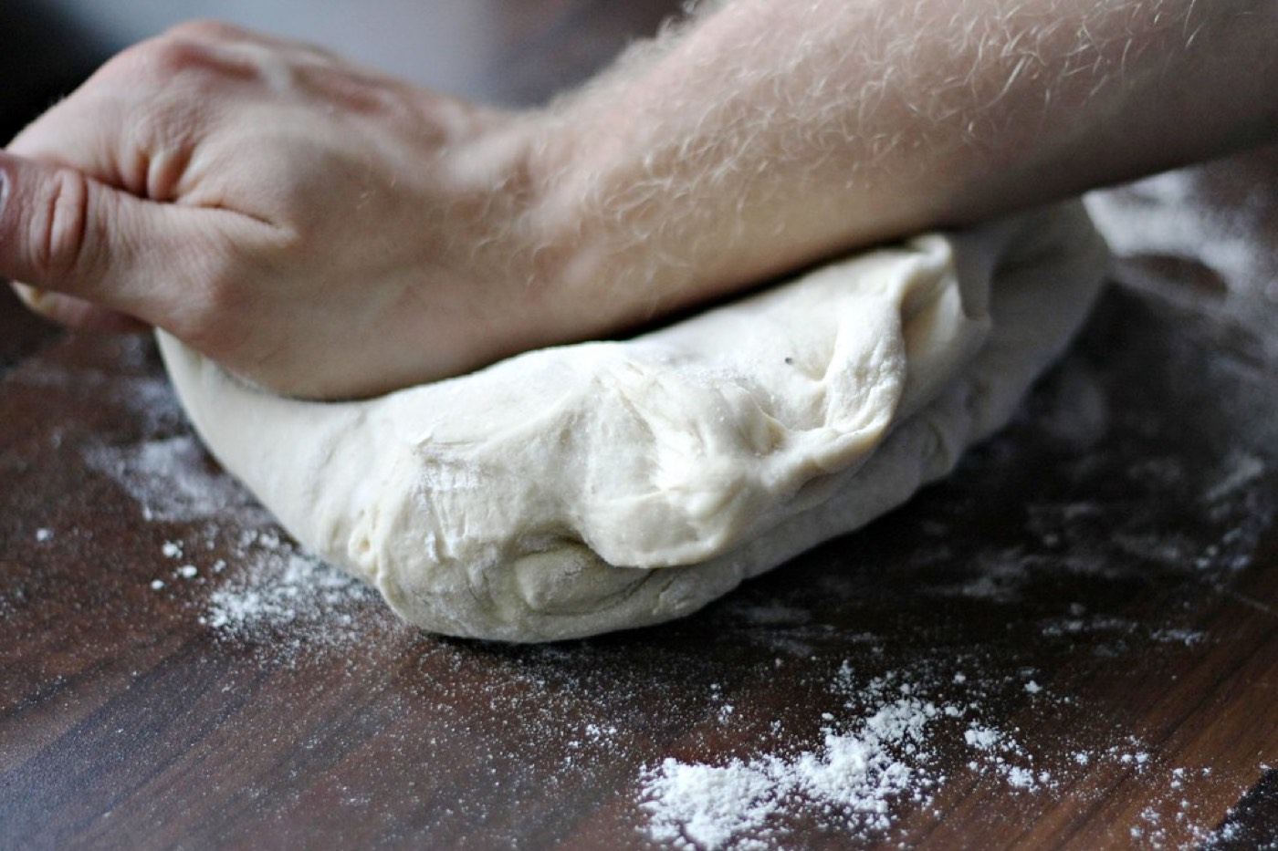 Hands kneading dough on a floured board