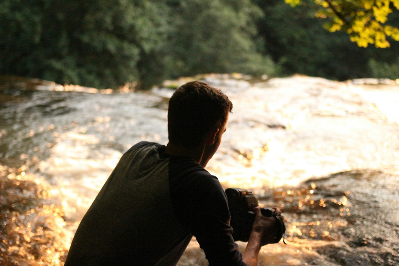 A photographer with camera in hand beside golden water