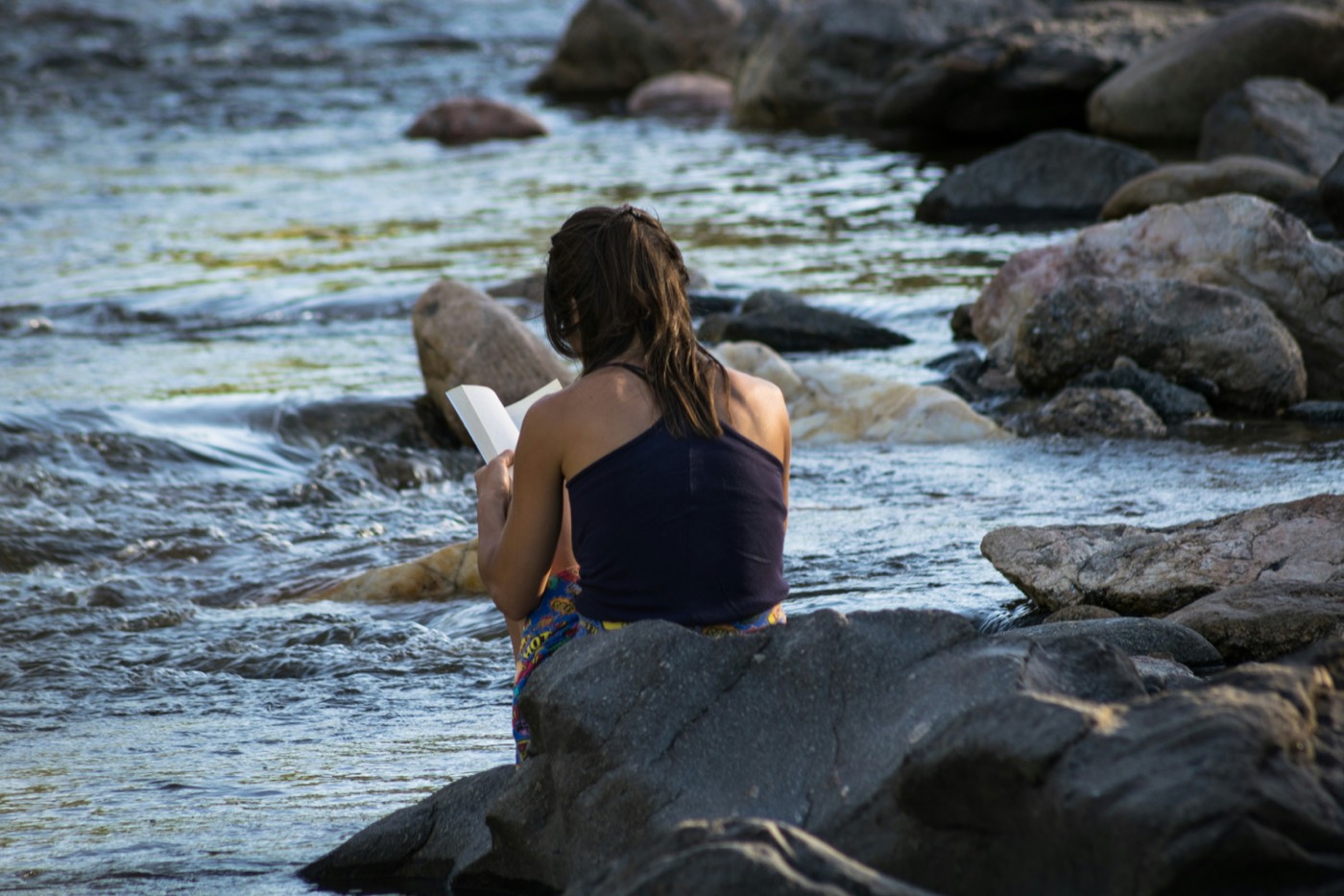 Reading on the river rocks