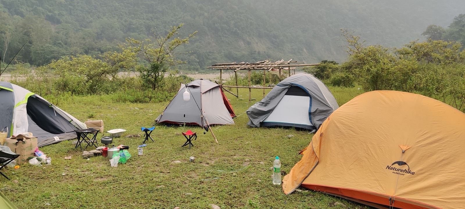 Tents pitched on the grassy bank above the riverbed
